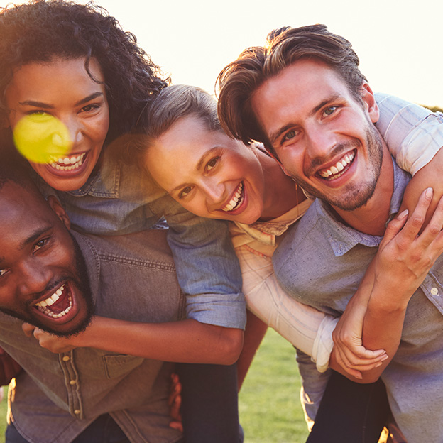 Group of Friends happy looking at the camera in a green grass field on a sunny day