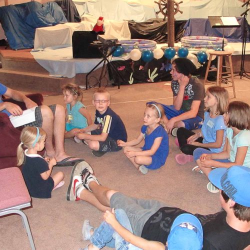 Group of kids sitting on the floor listening to a HAC member read during bible studies